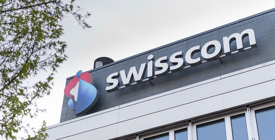La photo montre une partie du bâtiment Swisscom à Worblaufen, avec le logo de Swisscom.