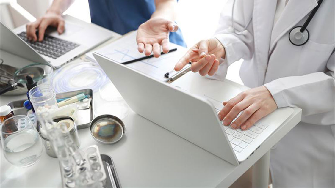 Sur l'image, on peut voir un médecin et une infirmière devant un ordinateur portable.