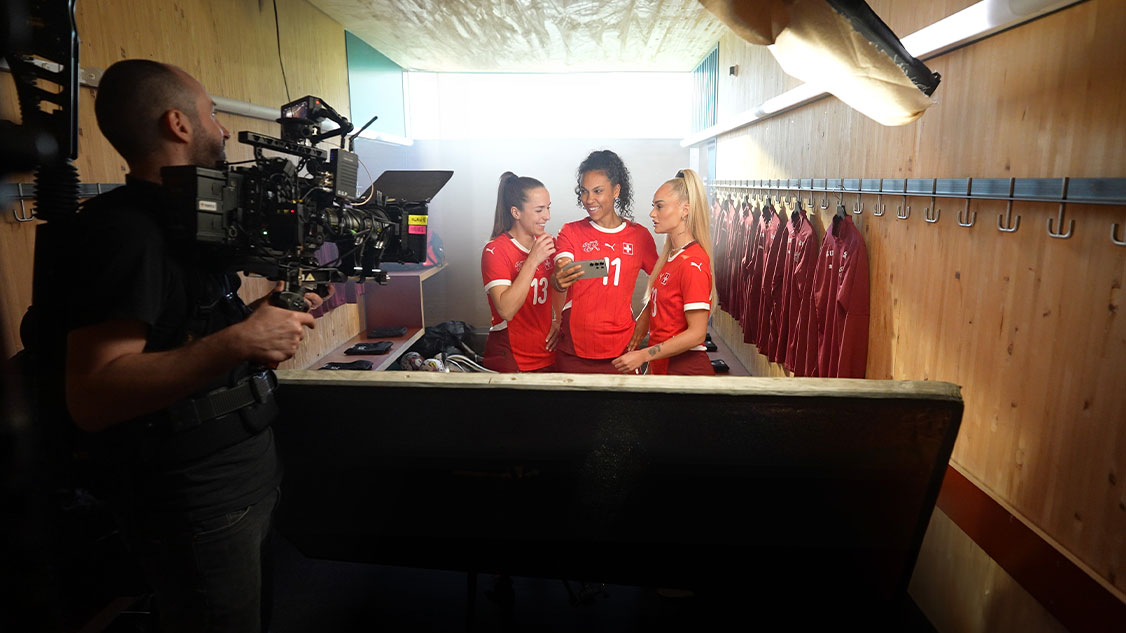 Auf dem Bild sind drei Vertreternnen des Frauen-Fussballnationalteams zu sehen, die gefilmt werden.
