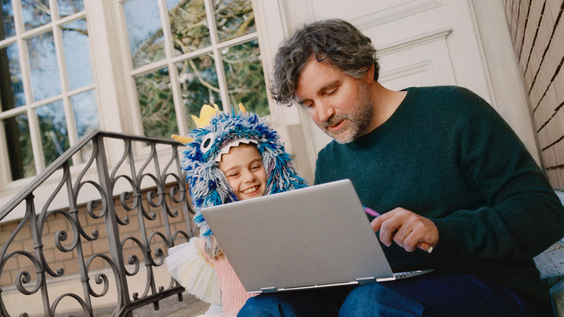 Petite fille déguisée en princesse des monstres, découvre une histoire sur son ordinateur portable avec son père