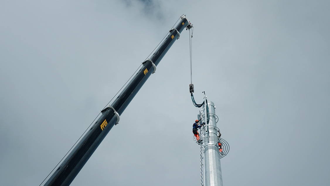 La photo présente l’installation des éléments d’antenne sur le mât.