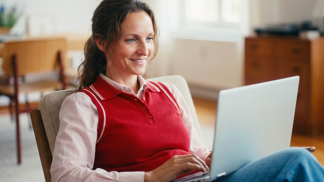 Frau sitzt am Laptop und nutzt das mit My Security von Swisscom geschützte Gerät.
