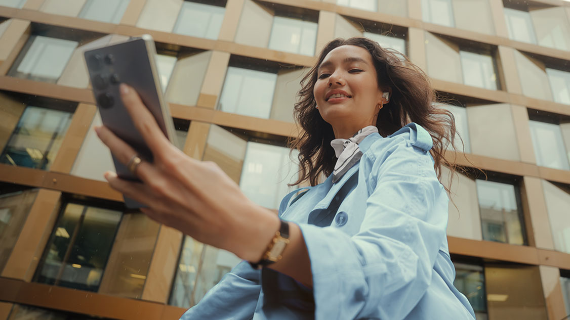 Eine Frau schaut unterwegs auf ihr Handy-Display.