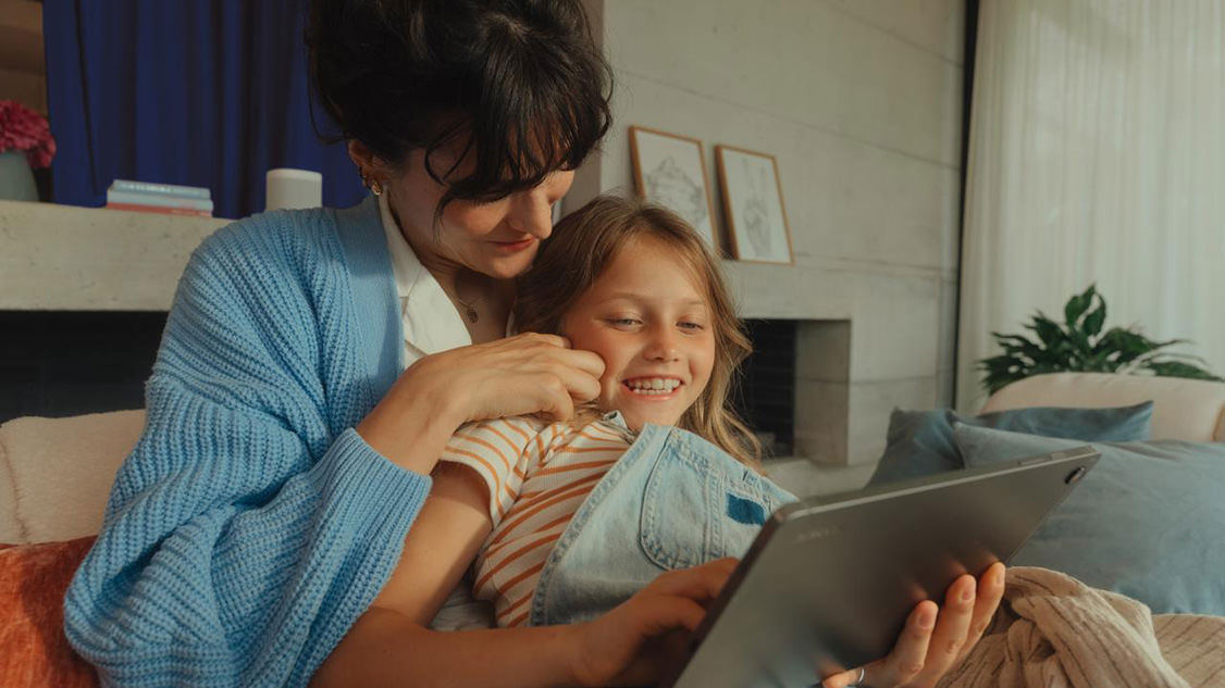 Eine Mutter und ein Kind betrachten gemeinsam etwas auf einem Tablet.