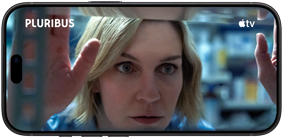 iPhone 18 Pro, mode paysage, affichant un gros plan d’une femme regardant à travers une étagère. Nom de la série : Pluribus