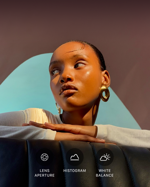 Primo piano di una persona ben illuminata su uno sfondo colorato, a mostrare l’interfaccia dei controlli professionali del sistema di fotocamere Pro: apertura dell’obiettivo, istogramma e bilanciamento del bianco