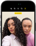 iPhone 18 Pro nero mostrato di fronte, sul display due persone in posa davanti alla fotocamera frontale Center Stage