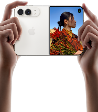 iPhone Duo, Farbe Sternenweiss, in zwei Händen im Querformat gehalten, aufgefaltet, linke Seite mit 48 MP Dual Fusion Rückkameras, rechte Seite zeigt eine Person, die fotografiert wird, auf dem äusseren Display kann die fotografierte Person während der Aufnahme mit Duo Preview ihr Gesicht sehen