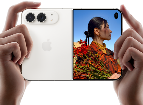 iPhone Duo, Farbe Sternenweiss, in zwei Händen im Querformat gehalten, aufgefaltet, linke Seite mit 48 MP Dual Fusion Rückkameras, rechte Seite zeigt eine Person, die fotografiert wird, auf dem äusseren Display kann die fotografierte Person während der Aufnahme mit Duo Preview ihr Gesicht sehen