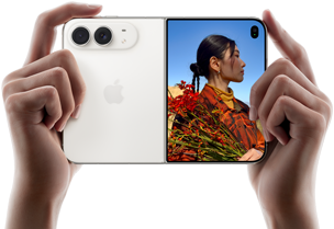 iPhone Duo, Farbe Sternenweiss, in zwei Händen im Querformat gehalten, aufgefaltet, linke Seite mit 48 MP Dual Fusion Rückkameras, rechte Seite zeigt eine Person, die fotografiert wird, auf dem äusseren Display kann die fotografierte Person während der Aufnahme mit Duo Preview ihr Gesicht sehen