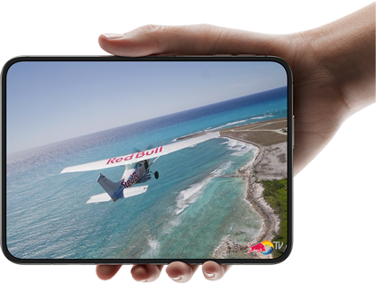 iPhone Duo, held with one hand, opened in horizontal orientation, fully unfolded, interior screen displays a photo of a plane flying over a beach.