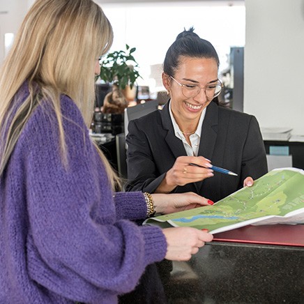 Hotel employee and female hotel guest looking at map at reception 