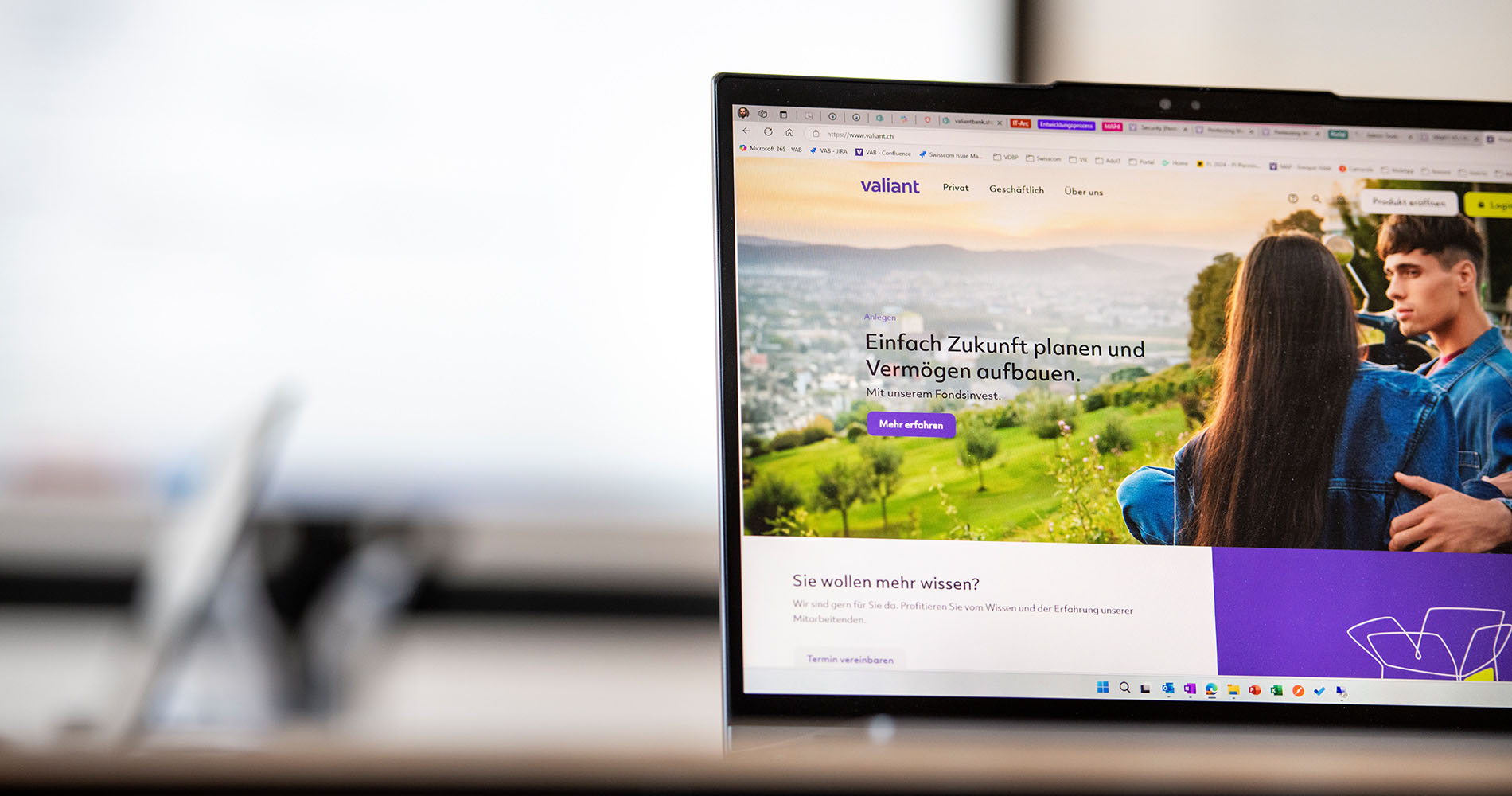 Auf einem Tisch steht ein Bildschirm, der die Startseite der Valiant-Website zeigt.