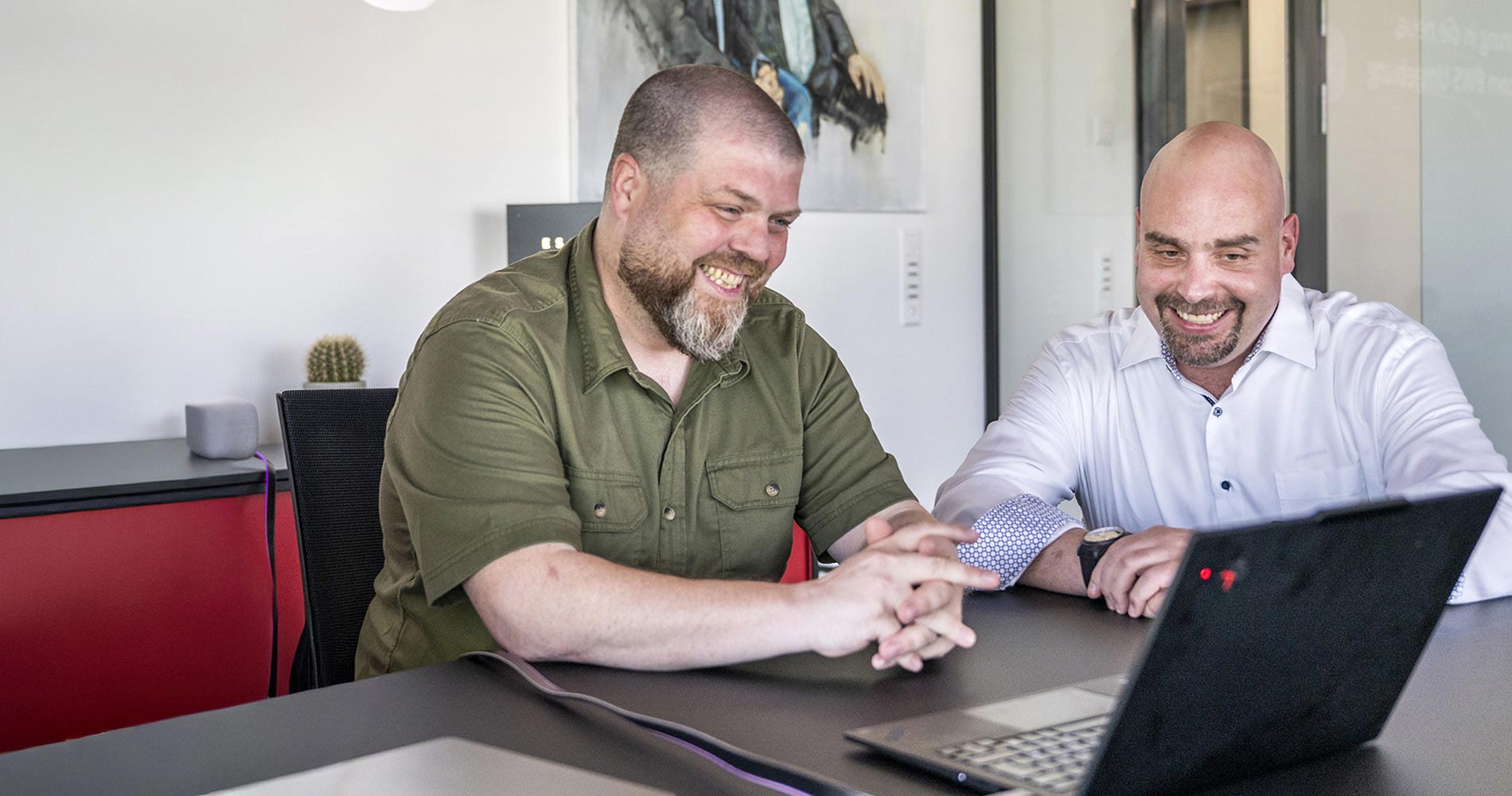 Michael Kamber (Senior Solution & System Engineer bei Swisscom) und Marcel Dätwyler sitzen gemeinsam an einem Tisch und schauen auf einen Laptop-Screen.