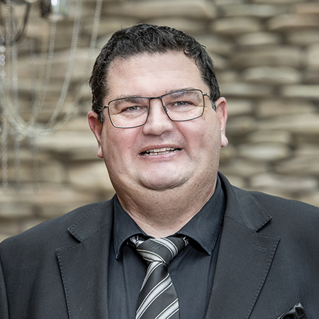 Portrait of Fabian Zubriggen, wearing glasses and a stripy tie