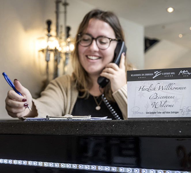 An employee at the hotel reception desk speaks on the telephone.