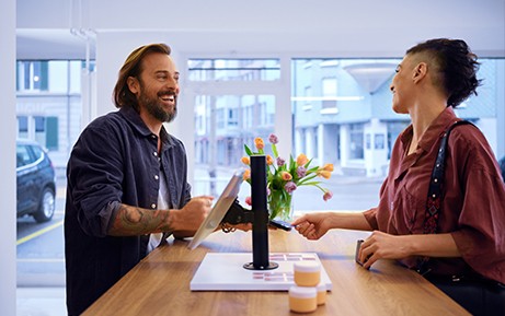 Una cliente paga al venditore con metodo contactless al bancone