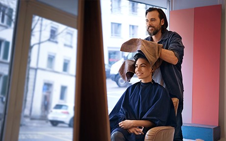 Un parrucchiere asciuga i capelli di una cliente