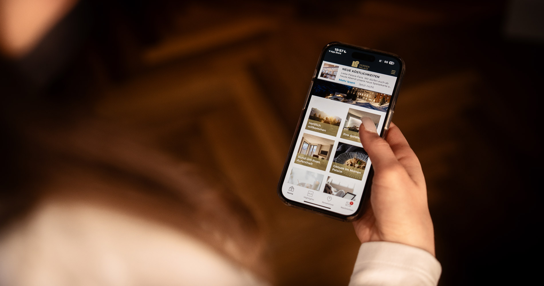 woman’s hand holding a mobile phone. The display shows the Hotel Mürren Palace’s digital guest directory.